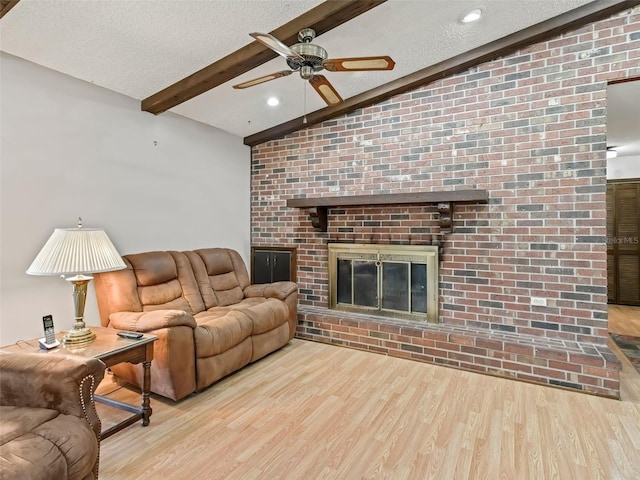 living room featuring brick wall, a brick fireplace, light hardwood / wood-style floors, and lofted ceiling with beams