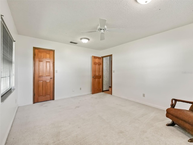 carpeted bedroom featuring ceiling fan and a textured ceiling