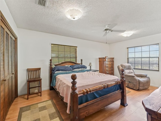 bedroom featuring a textured ceiling, a closet, ceiling fan, and light hardwood / wood-style flooring