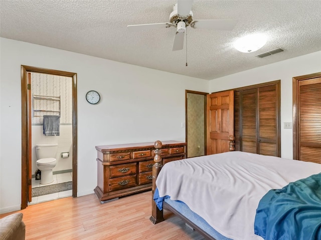 bedroom featuring ceiling fan, connected bathroom, multiple closets, light hardwood / wood-style flooring, and a textured ceiling