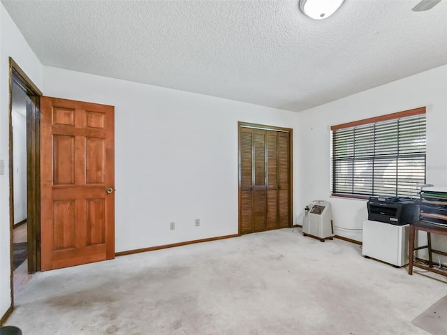 interior space featuring a textured ceiling, light colored carpet, and ceiling fan