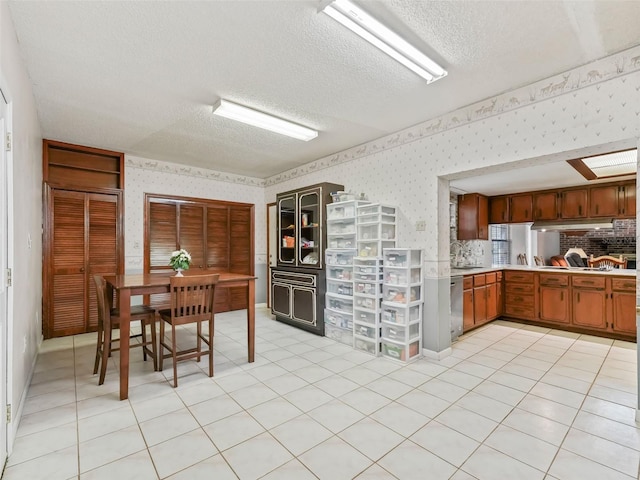 kitchen with sink, light tile floors, dishwasher, backsplash, and a textured ceiling