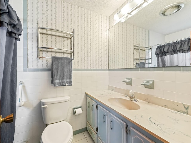 bathroom featuring tile walls, tile floors, a textured ceiling, toilet, and oversized vanity