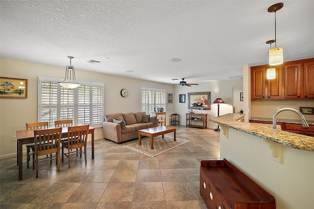 living room featuring tile floors, ceiling fan, a textured ceiling, and sink