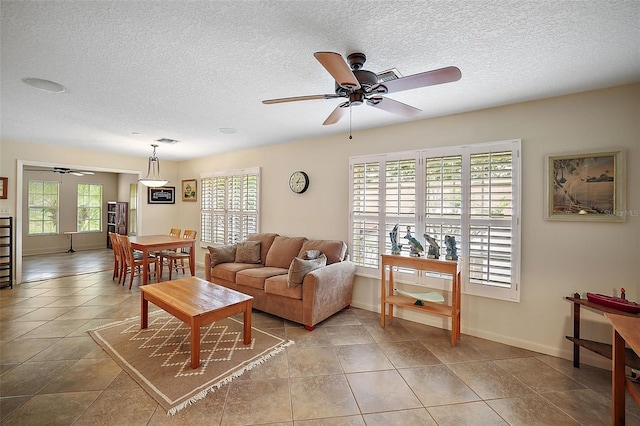 tiled living room with plenty of natural light, ceiling fan, and a textured ceiling