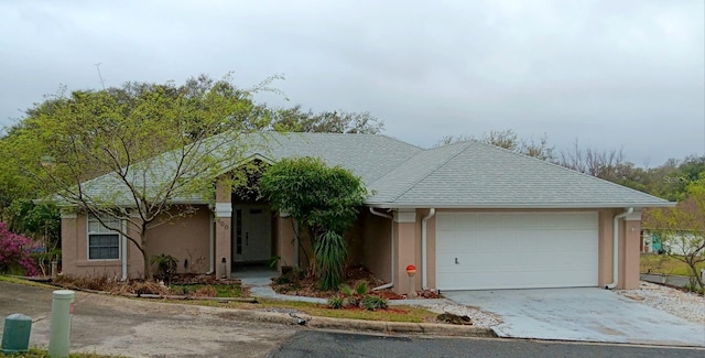 ranch-style home with a garage, roof with shingles, and stucco siding