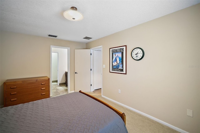 bedroom with a textured ceiling, light colored carpet, visible vents, and baseboards