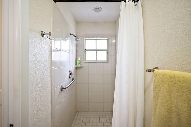 full bathroom featuring a textured wall and a stall shower