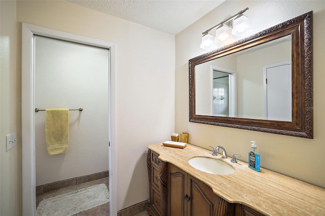 bathroom with a textured ceiling, vanity, and baseboards