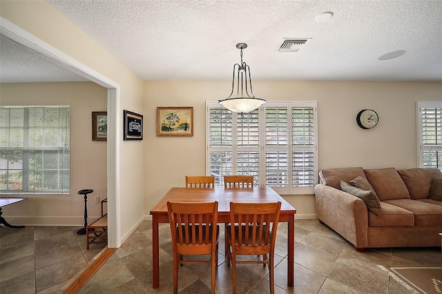 dining space featuring baseboards, visible vents, and a textured ceiling