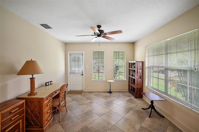 home office featuring a ceiling fan, plenty of natural light, visible vents, and a textured ceiling