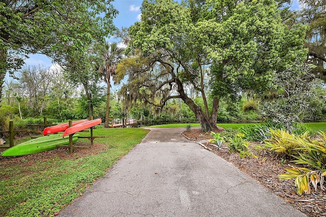 surrounding community with aphalt driveway and a yard