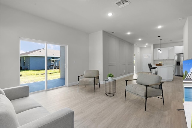 living room with light hardwood / wood-style floors and sink