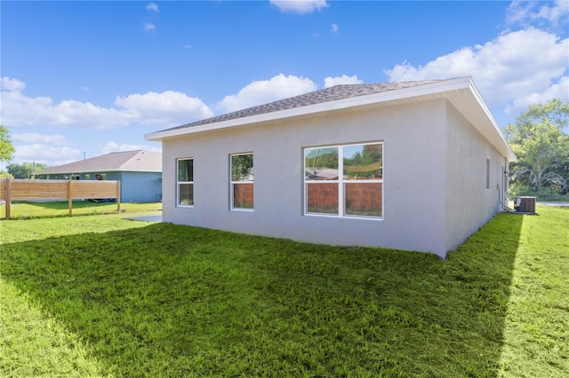 back of property featuring central air condition unit and a yard