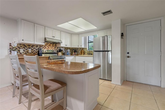 kitchen featuring tasteful backsplash, a breakfast bar, appliances with stainless steel finishes, and white cabinetry