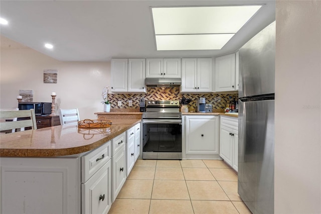 kitchen featuring appliances with stainless steel finishes, backsplash, light tile floors, white cabinetry, and light stone countertops