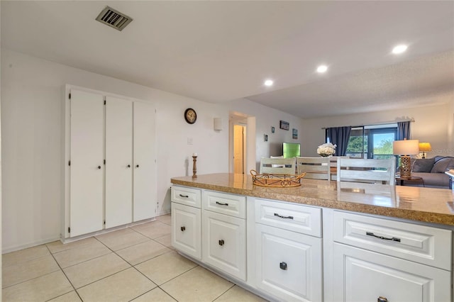 kitchen with light tile flooring, white cabinetry, and light stone countertops