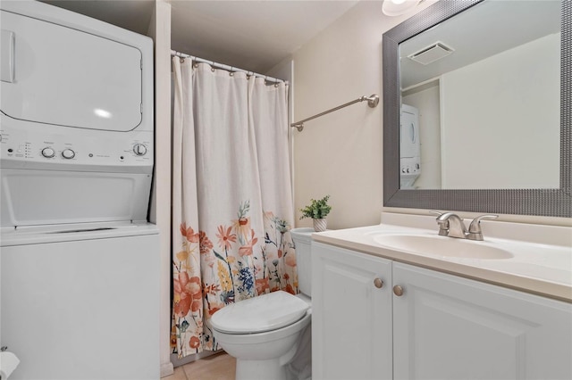 bathroom with tile flooring, toilet, vanity with extensive cabinet space, and stacked washer / drying machine