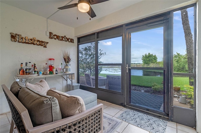 sunroom featuring ceiling fan and a water view