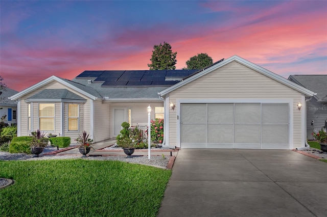 single story home featuring solar panels, a garage, and a lawn