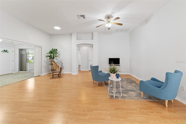 sitting room with ceiling fan, light wood-type flooring, and a textured ceiling