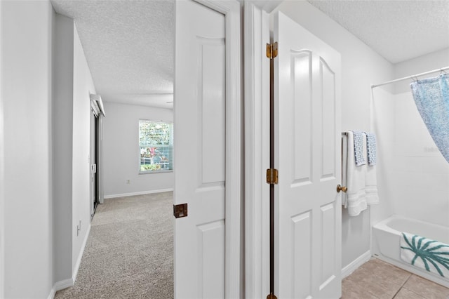 hallway with light carpet and a textured ceiling