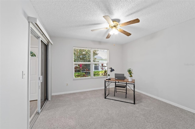 carpeted office space with a textured ceiling and ceiling fan