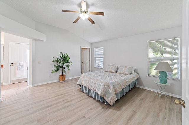 bedroom featuring lofted ceiling, ceiling fan, light wood-type flooring, and a textured ceiling