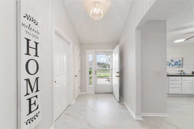 entrance foyer with a textured ceiling, vaulted ceiling, and a notable chandelier