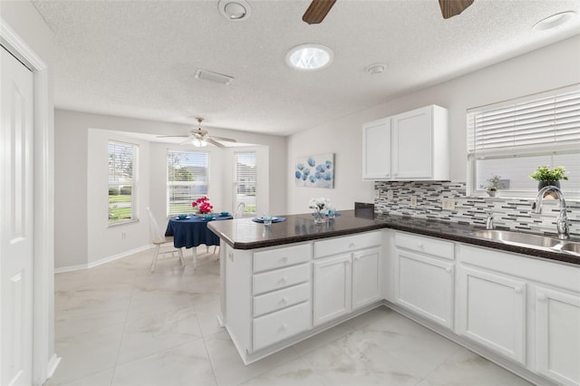 kitchen with white cabinets, sink, tasteful backsplash, a textured ceiling, and kitchen peninsula