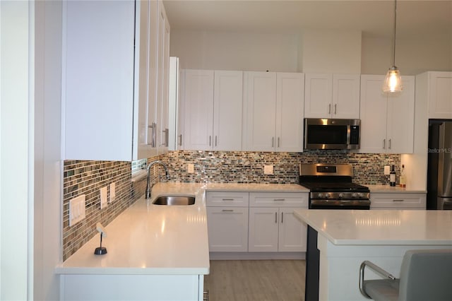 kitchen with white cabinetry, appliances with stainless steel finishes, backsplash, light wood-type flooring, and sink