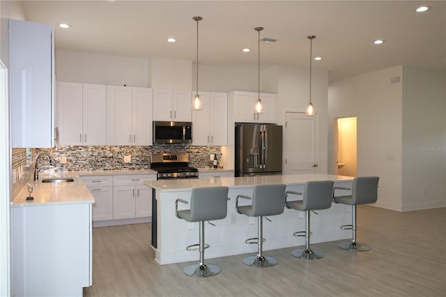 kitchen with sink, white cabinets, appliances with stainless steel finishes, tasteful backsplash, and light wood-type flooring