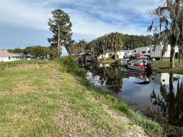 view of dock with a water view and a yard