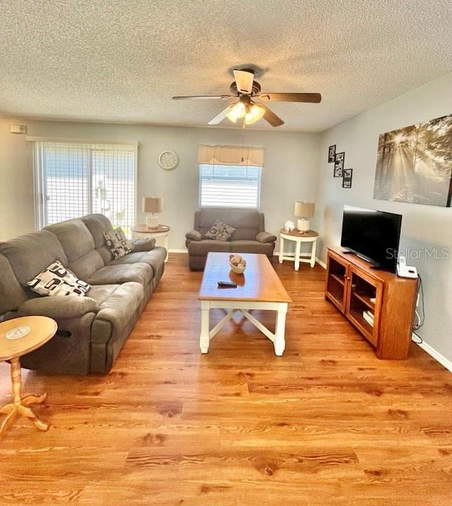 living room featuring a textured ceiling, ceiling fan, and light wood-type flooring