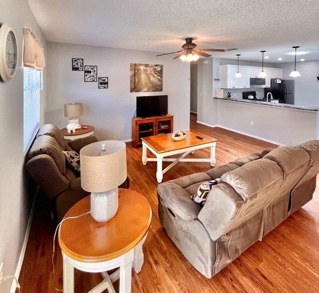 living room featuring a textured ceiling, ceiling fan, and light hardwood / wood-style flooring