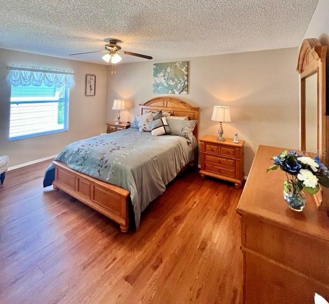 bedroom featuring dark hardwood / wood-style flooring, ceiling fan, and a textured ceiling