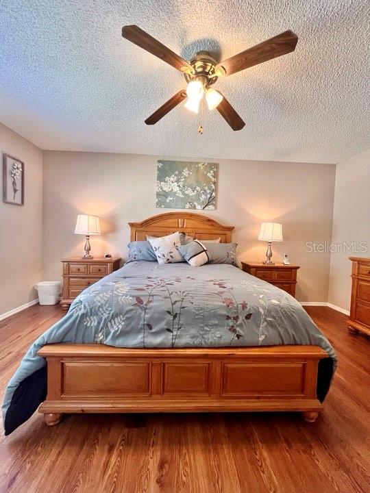 bedroom with hardwood / wood-style floors, a textured ceiling, and ceiling fan