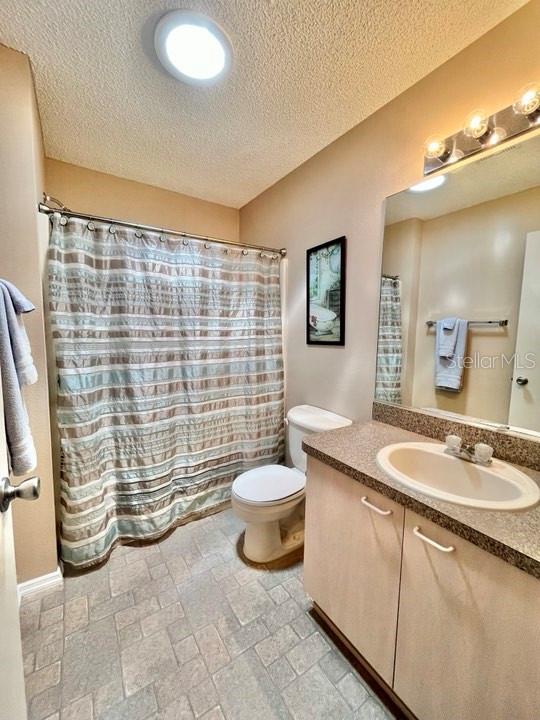 bathroom featuring a textured ceiling, toilet, tile floors, and vanity with extensive cabinet space