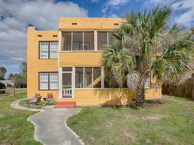 view of front facade featuring a sunroom and a front lawn