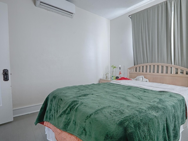 bedroom featuring hardwood / wood-style floors and an AC wall unit