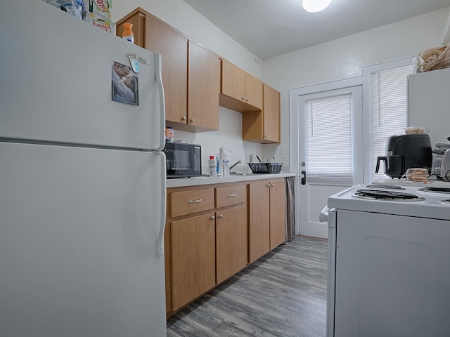 kitchen featuring light brown cabinets, white appliances, and light wood-type flooring