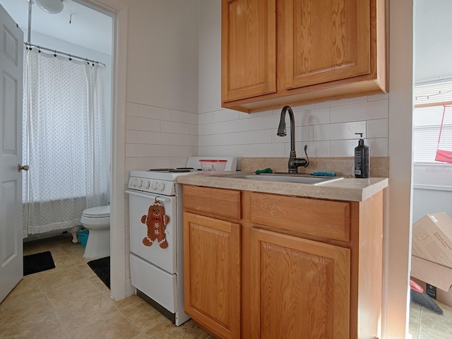 kitchen featuring tasteful backsplash, light tile floors, sink, and white range