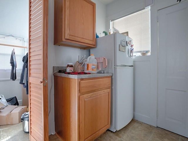 kitchen featuring white refrigerator and light tile floors