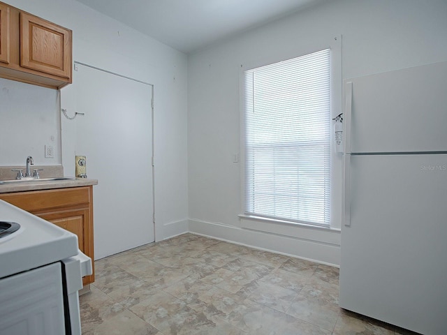 kitchen with light tile floors, white refrigerator, and sink