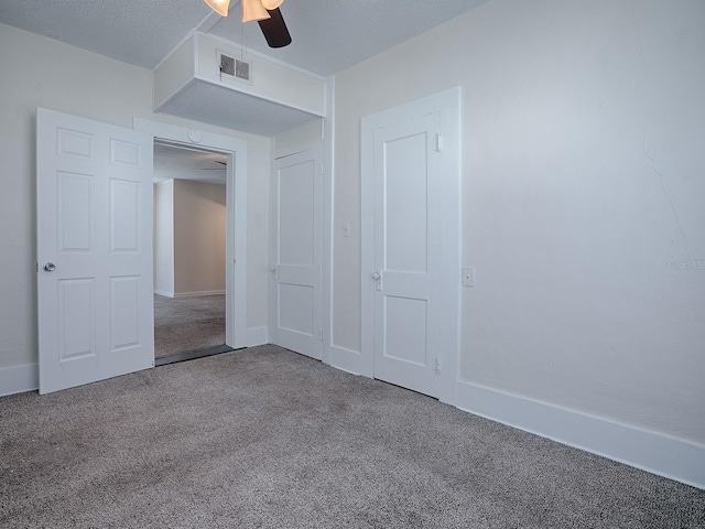 unfurnished bedroom with a textured ceiling, a closet, ceiling fan, and dark carpet