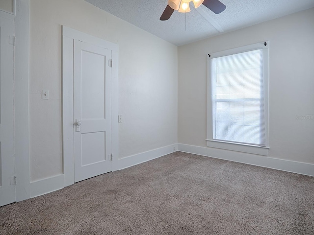 carpeted empty room featuring ceiling fan and a textured ceiling