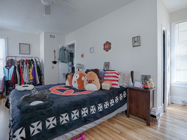 bedroom featuring ceiling fan, multiple windows, and light wood-type flooring