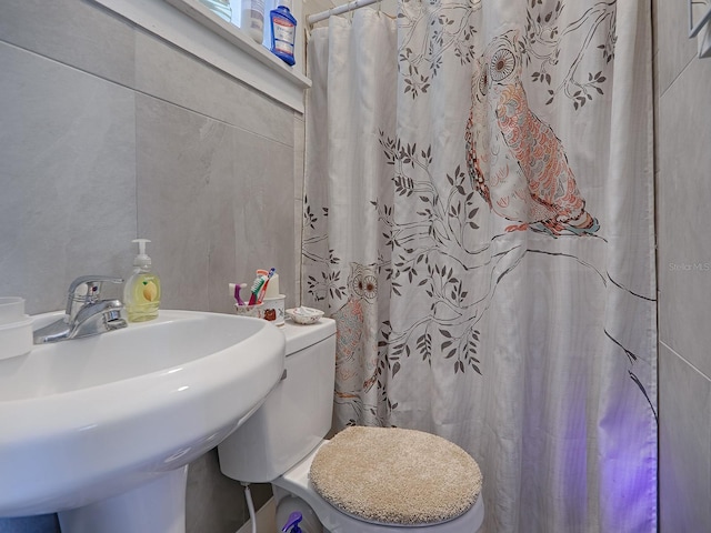 bathroom featuring tile walls, toilet, and sink