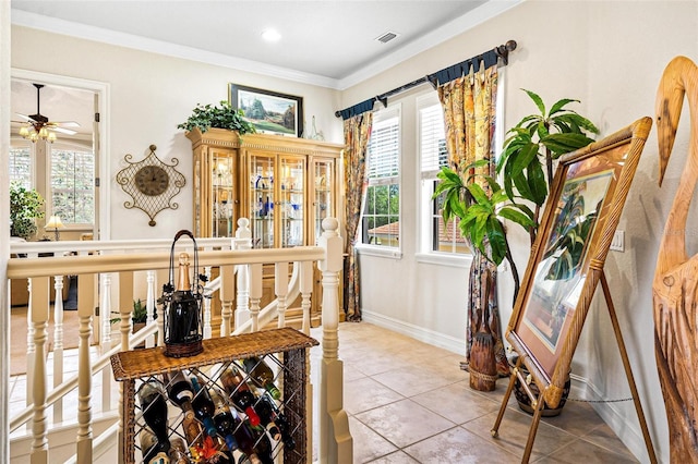 wine room with ceiling fan, a healthy amount of sunlight, crown molding, and light tile floors