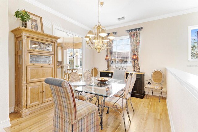 dining area featuring crown molding, an inviting chandelier, and light hardwood / wood-style flooring